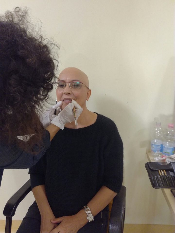 Annarita Minutaglio trucca a pennello le labbra di una donna in terapia oncologica